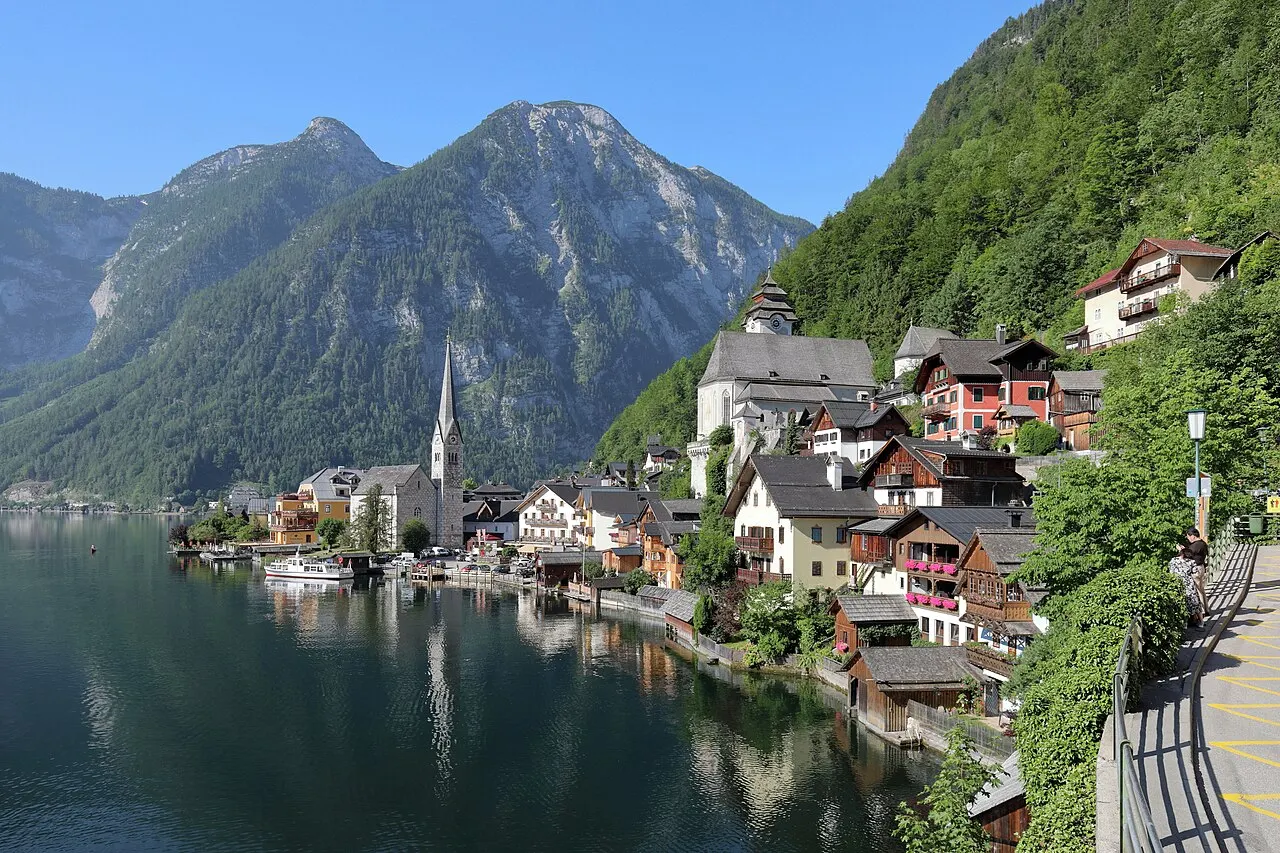 Le village de Hallstatt au bord de son lac, avec son clocher et ses montagnes boisées